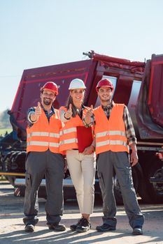 Colleagues in a freight forwarding company giving thumbs up in front of trucks