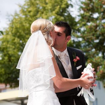 Happy wedding couple, they are holding doves in their hands and want to let them fly free as a symbol of love, and they are kissing each other