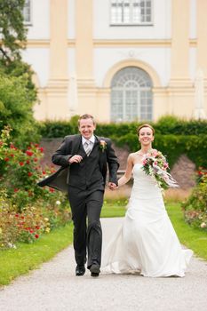 Newlywed couple - bride and groom - in a park running into a future (child, dissent, divorce etc.)