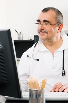 Doctor in his office looking at a computer screen doing medical research