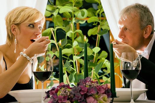 Couple having dinner in a restaurant, candles on the table, they are eating pasta