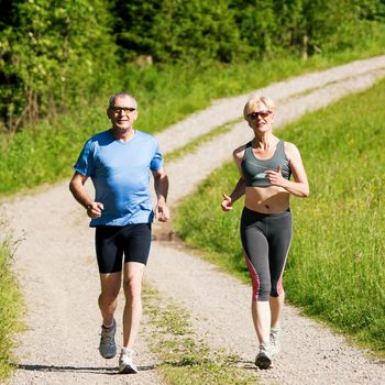 Mature or senior couple doing sport outdoors, jogging