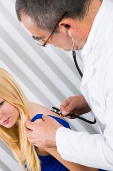 Doctor examining a female patient using a stethoscope