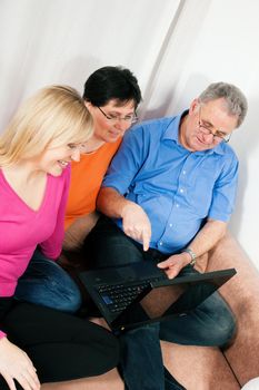 Family (parents and adult daughter) surfing the internet using a laptop