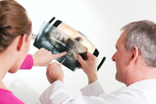 Dentist explaining the details of a x-ray picture to his patient, focus on eyes of doctor