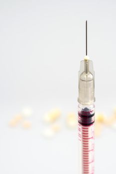 Syringe, injection needle and some pill on white background