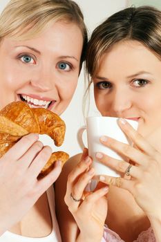 Two girls having coffee and croissants for breakfast