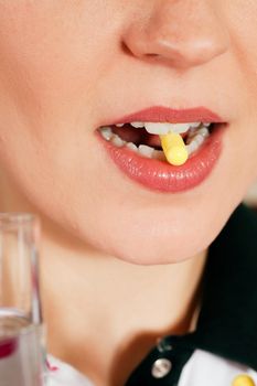 Woman taking in a pharmaceutical pill (close up on mouth) for medicine, health concept