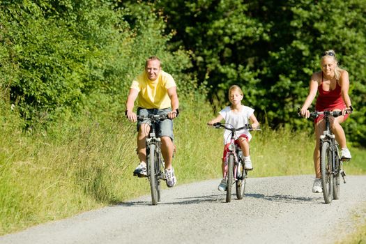Family with two kids riding their bicycles on a summer day