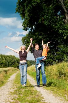 Happy family (mother, father and kid) having a walk in the nature