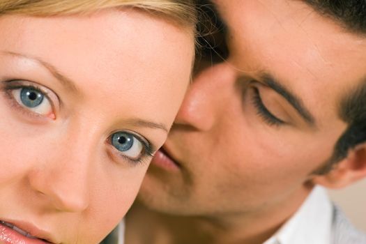 Young man whispering a secret (presumably something very romantic) in her ear