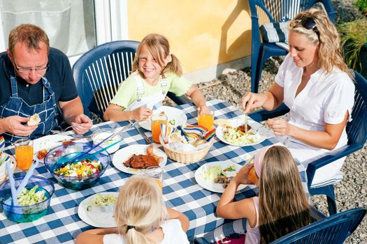 Family having dinner in their garden - barbecue stuff and salad