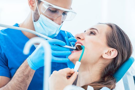 Side view close-up of a relaxed young woman during painless oral treatment in the modern dental office of an experienced and dedicated dentist