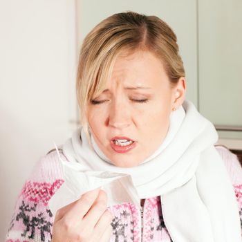Woman with a flu sneezing into her handkerchief