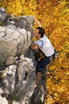 Man climbing a rock short before reaching the summit