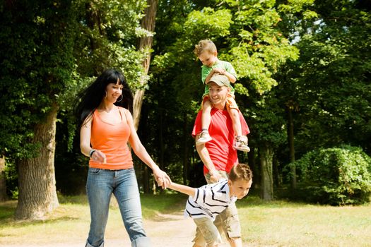 Family with two kids having a walk in the park (focus is on the boy in front!)