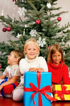 Family Christmas - three children having received gifts showing them around