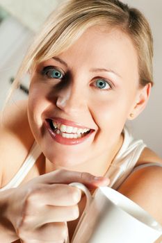 Gorgeous woman visibly enjoying a hot cup of coffee in the morning