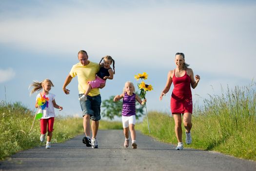 Family with three kids running down a hill