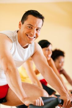 Group of three people - presumably friends - spinning in the gym, , exercising for their legs and cardio training