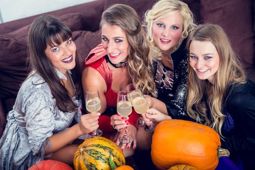 Young and beautiful woman posing funny and scary while toasting with her best friends during Halloween costume party