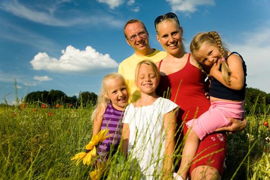 Happy family with tree kids standing in a field of wild flowers together - metaphor for love