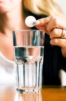 Woman ready to drop a pill into a glass of water (macro)