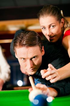 Couple (man and woman) in a billiard hall playing snooker