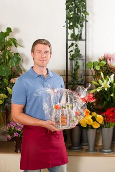 Male Florist in flower shop or nursery presenting his plants on display