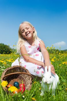 Easter bunny with eggs on a meadow in spring, loved by little girl