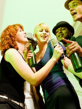 Group of friends (diversity) at a party in a club doing karaoke and drinking beer