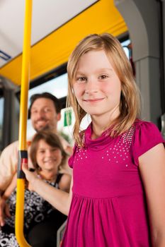 Child in a bus; in the background presumably her father and sister to be seen