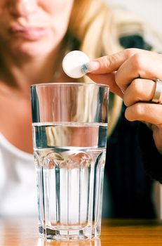 Woman trying to get rid of a bad hangover by using pharmaceuticals (macro)