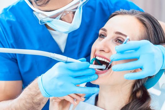 Side view close-up of a relaxed young woman during painless oral treatment in the modern dental office of an experienced and dedicated dentist