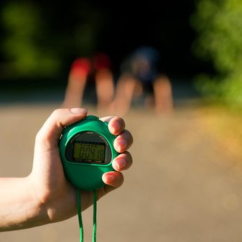 Young couple doing sport outdoors, attempting to run or sprint waiting for the start signal, a trainer is ready to measure their performance