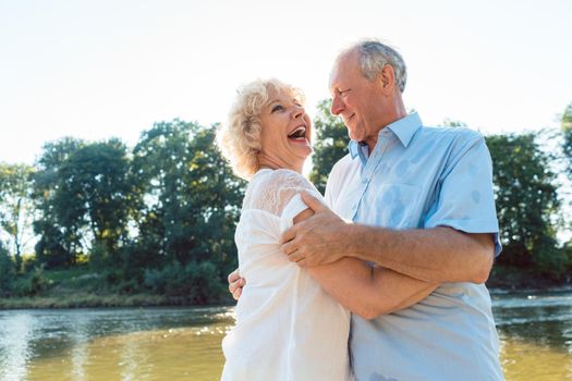 Low-angle side view portrait of a romantic senior couple in love enjoying a healthy and active lifestyle outdoors in summer