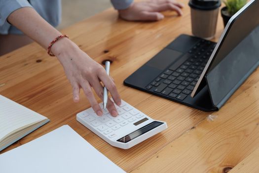 businesswoman working on desk office with using a calculator to calculate the numbers, finance accounting concept.