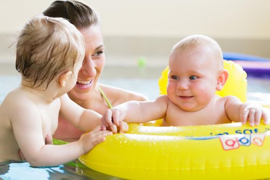 Mums and their children having fun together playing with toys at baby swimming lesson