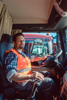 Lorry or truck driver sitting in the cabin of his vehicle driving