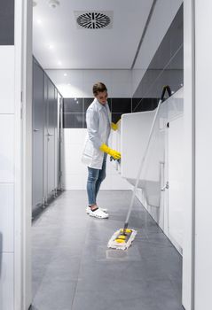 Janitor woman cleaning urinals in public mens toilet