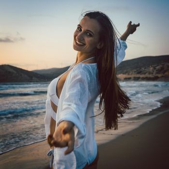 Woman having fun at the beach during sunset time spreading her arms