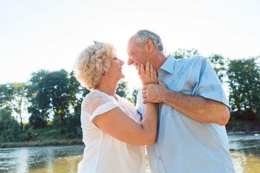 Low-angle side view portrait of a romantic senior couple in love enjoying a healthy and active lifestyle outdoors in summer