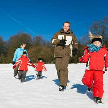 Active Family in winter running down a hill in the snow