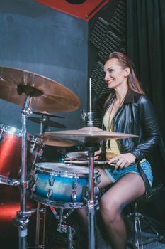 Woman playing the drums in music school rehearsal room