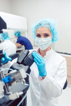 Woman doctor working on manipulator fertilizing human eggs in fertility clinic lab