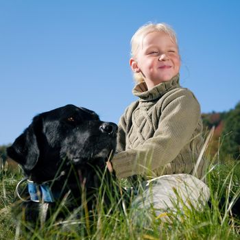 A little girl riding on her much larger dog, both looking into a clear blue sky