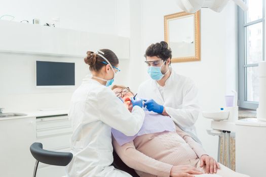 Dentist during treatment of senior patient woman looking into mouth