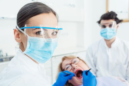 Dentist woman in her surgery with protective clothing