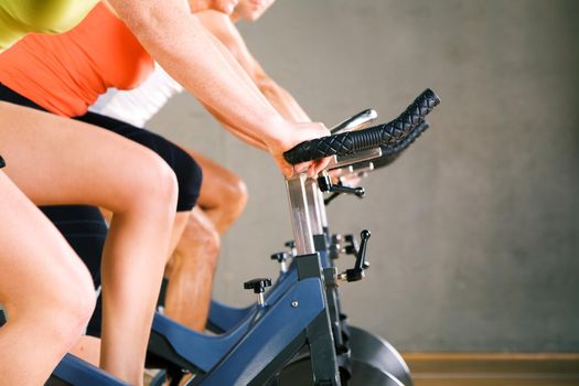 Three people working out on a stationary bicycle in the gym