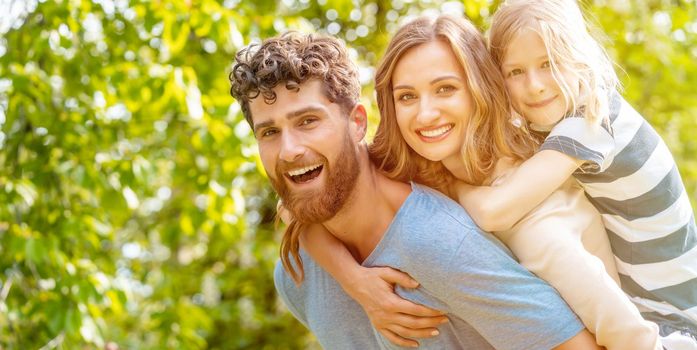 Strong and reliable man supporting his family by carrying wife and son piggyback